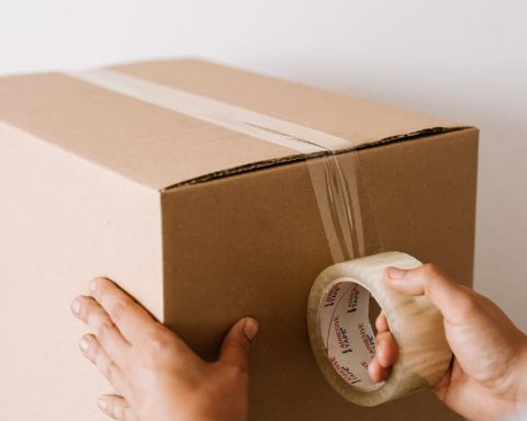 crop man sealing carton box with tape