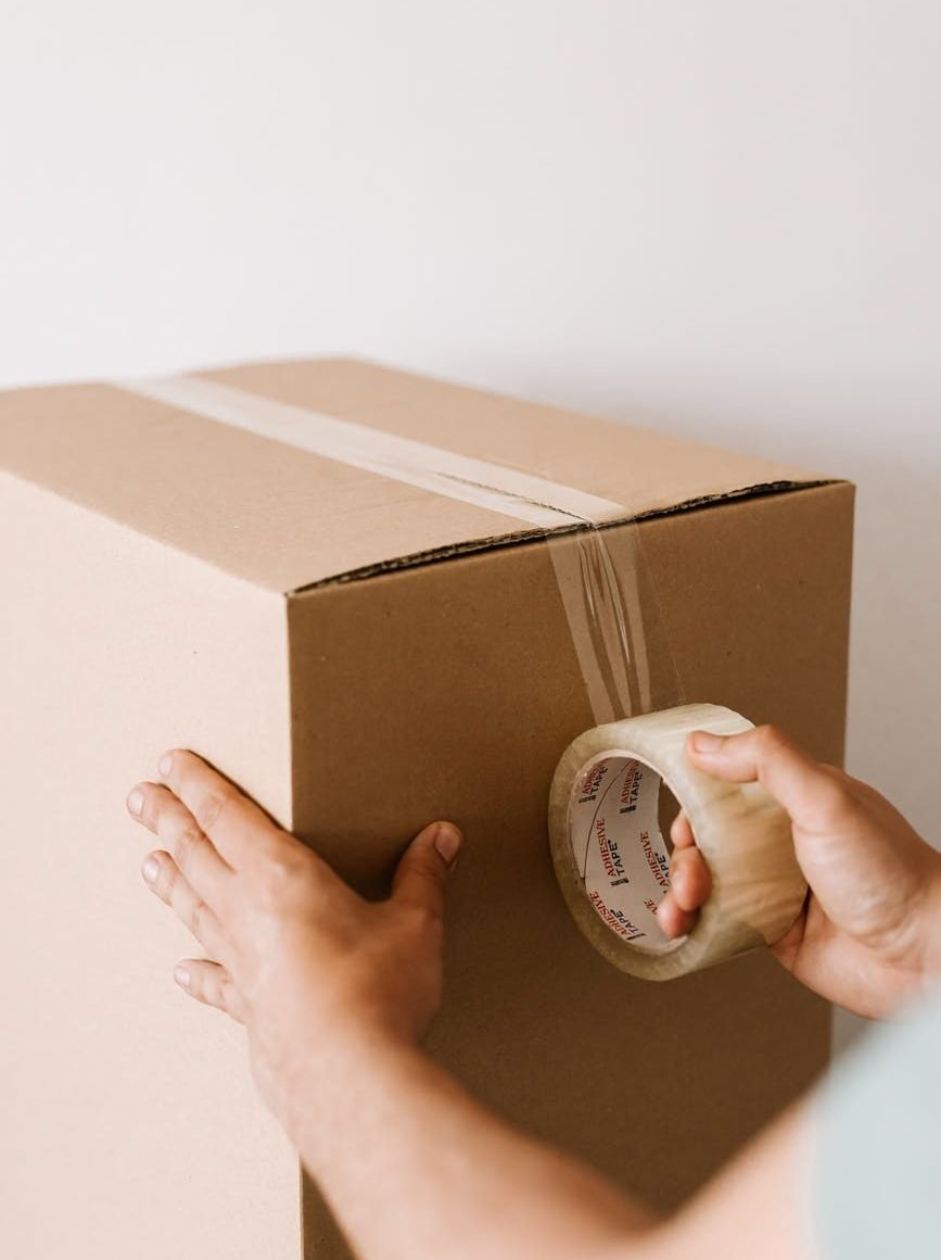 crop man sealing carton box with tape