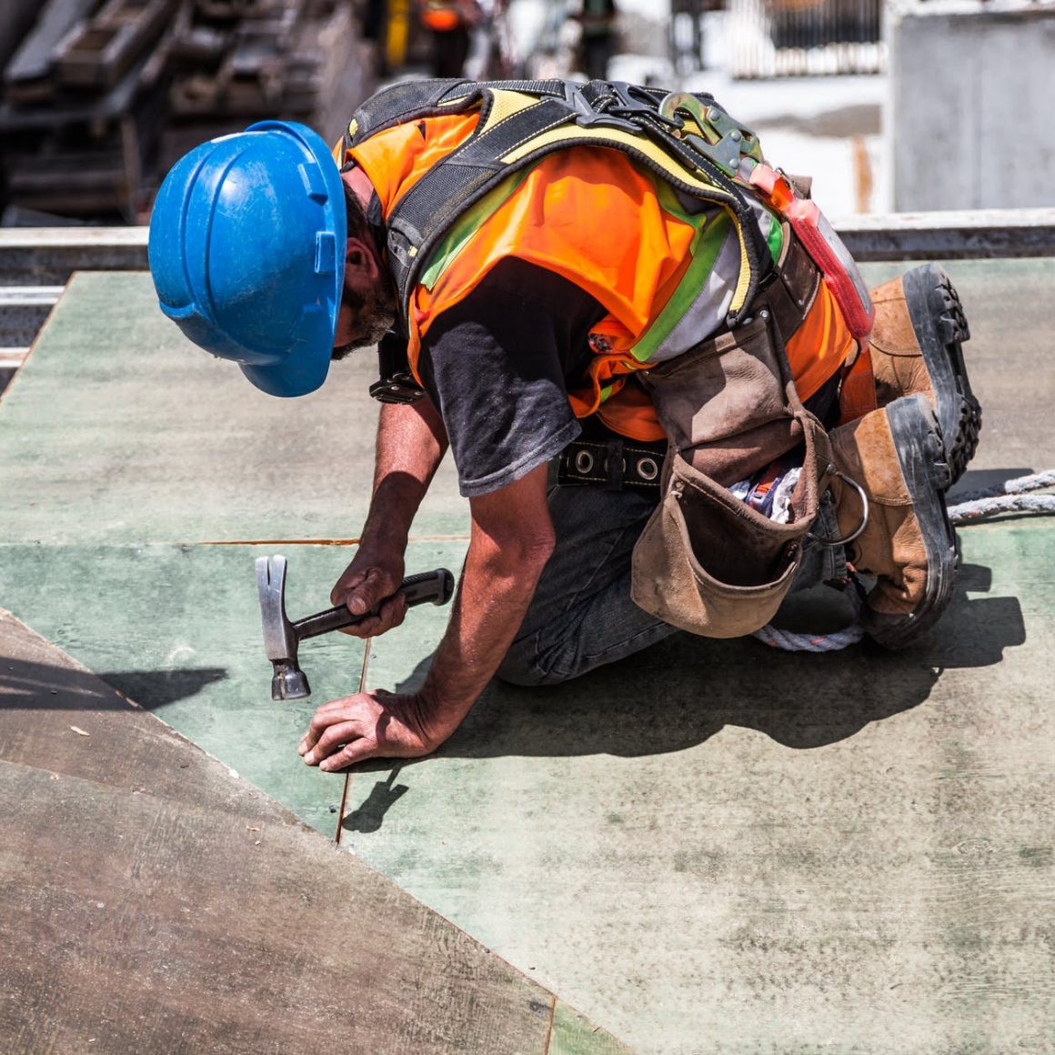 man wearing blue hard hat using hammer