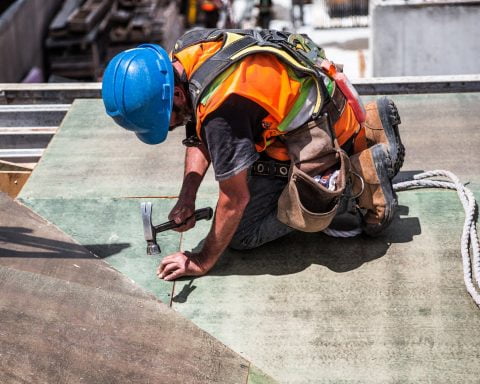man wearing blue hard hat using hammer