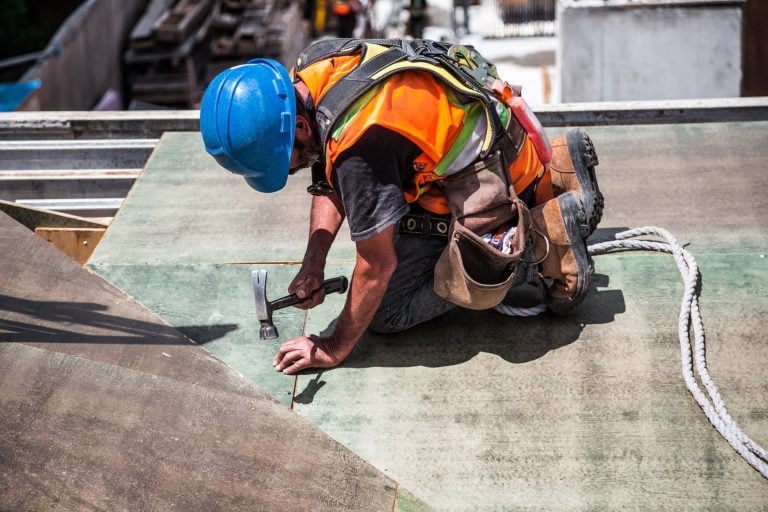 man wearing blue hard hat using hammer