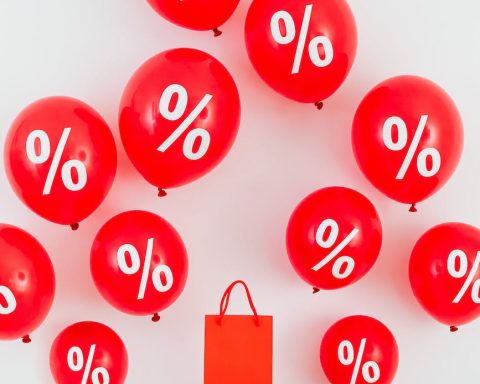 a red paper bag in the middle of red balloons with percentage symbols