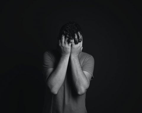 gray scale photo of man covering face with his hands