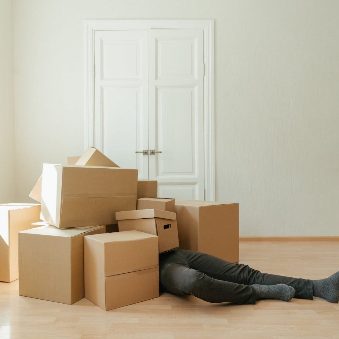 person in black leather boots lying on brown cardboard boxes