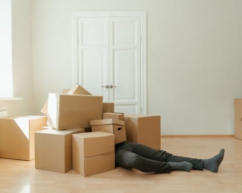 person in black leather boots lying on brown cardboard boxes