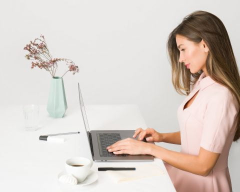 woman in pink dress using laptop computer