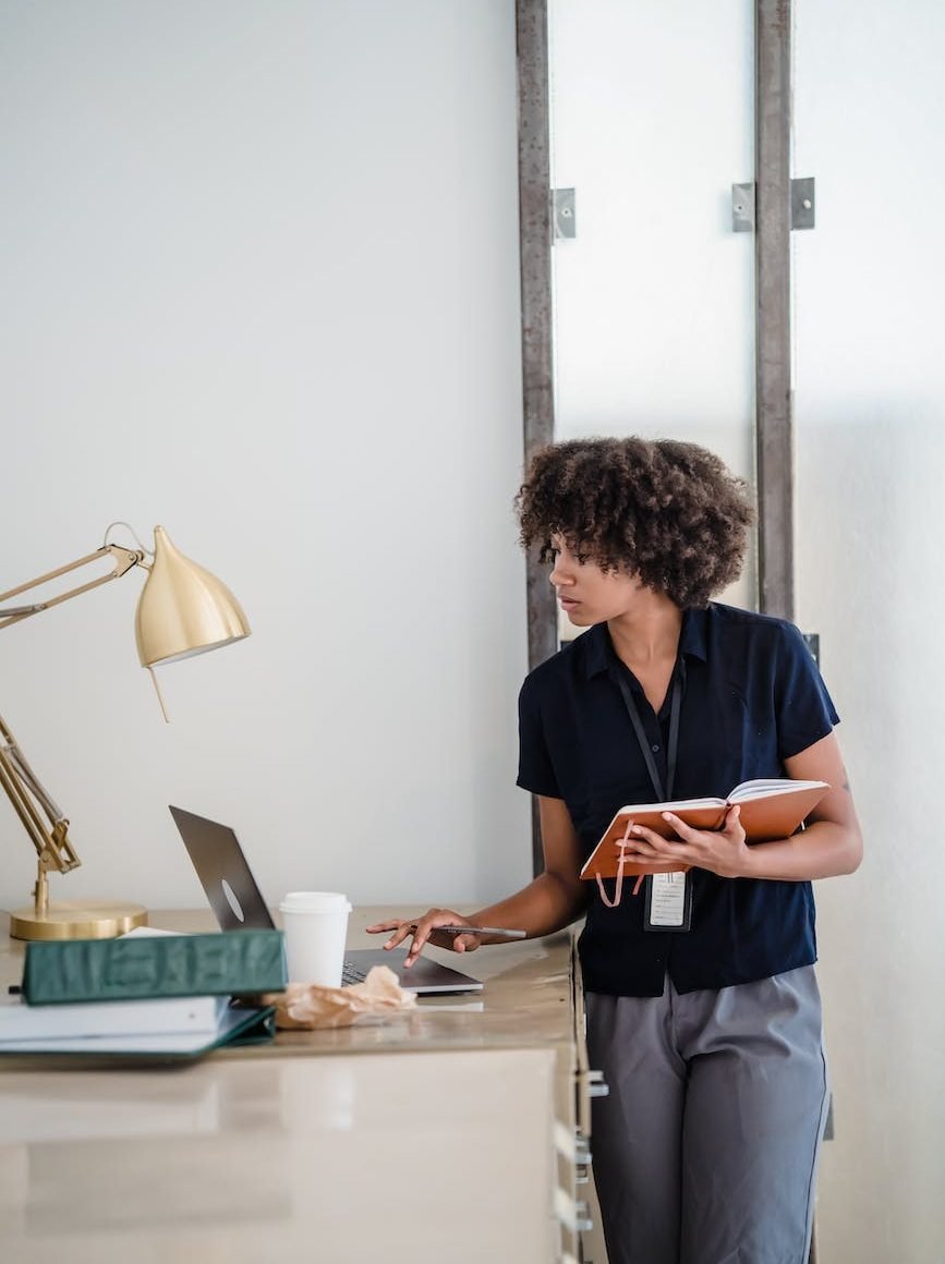 woman holding a notebook and using a laptop