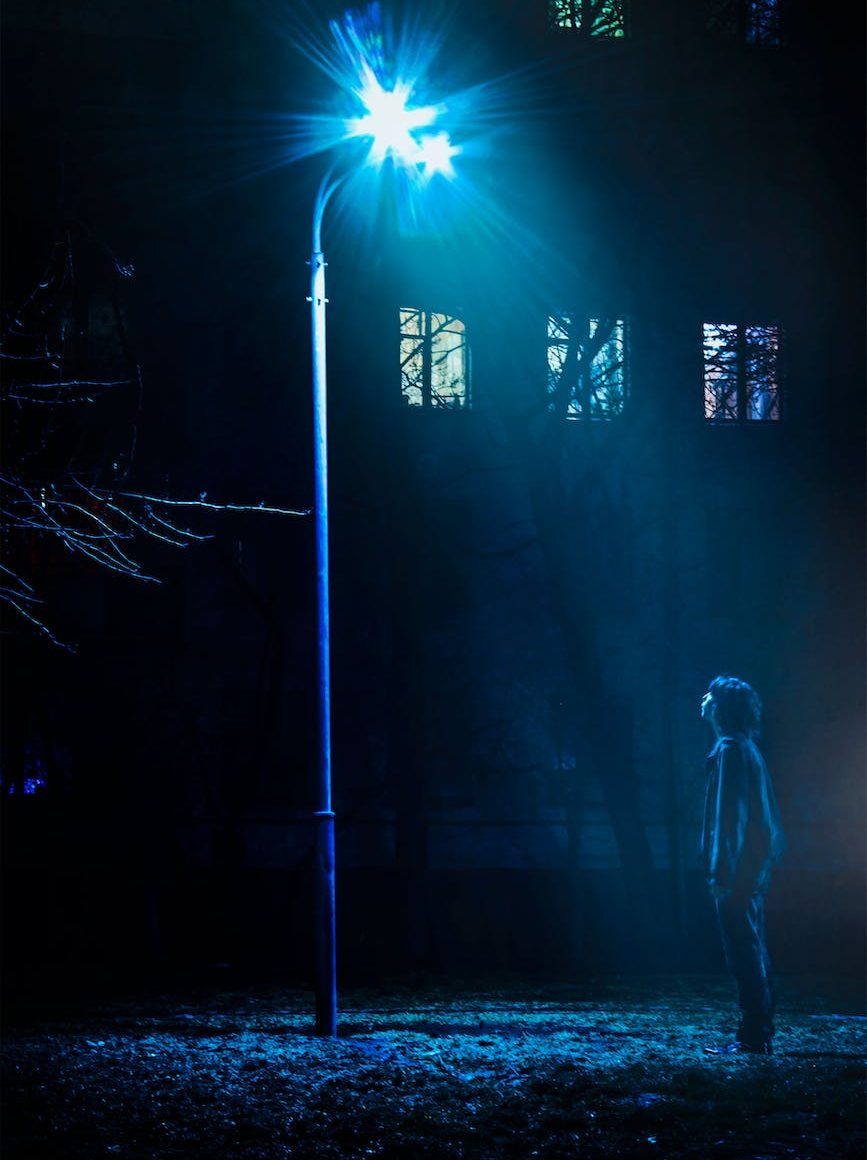 man standing in front of street light turned on