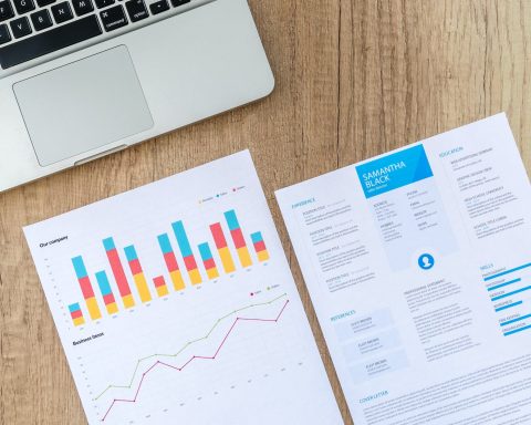 two white printer papers near macbook on brown surface