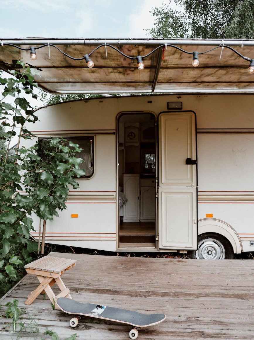 a skateboard on wooden deck near a white caravan