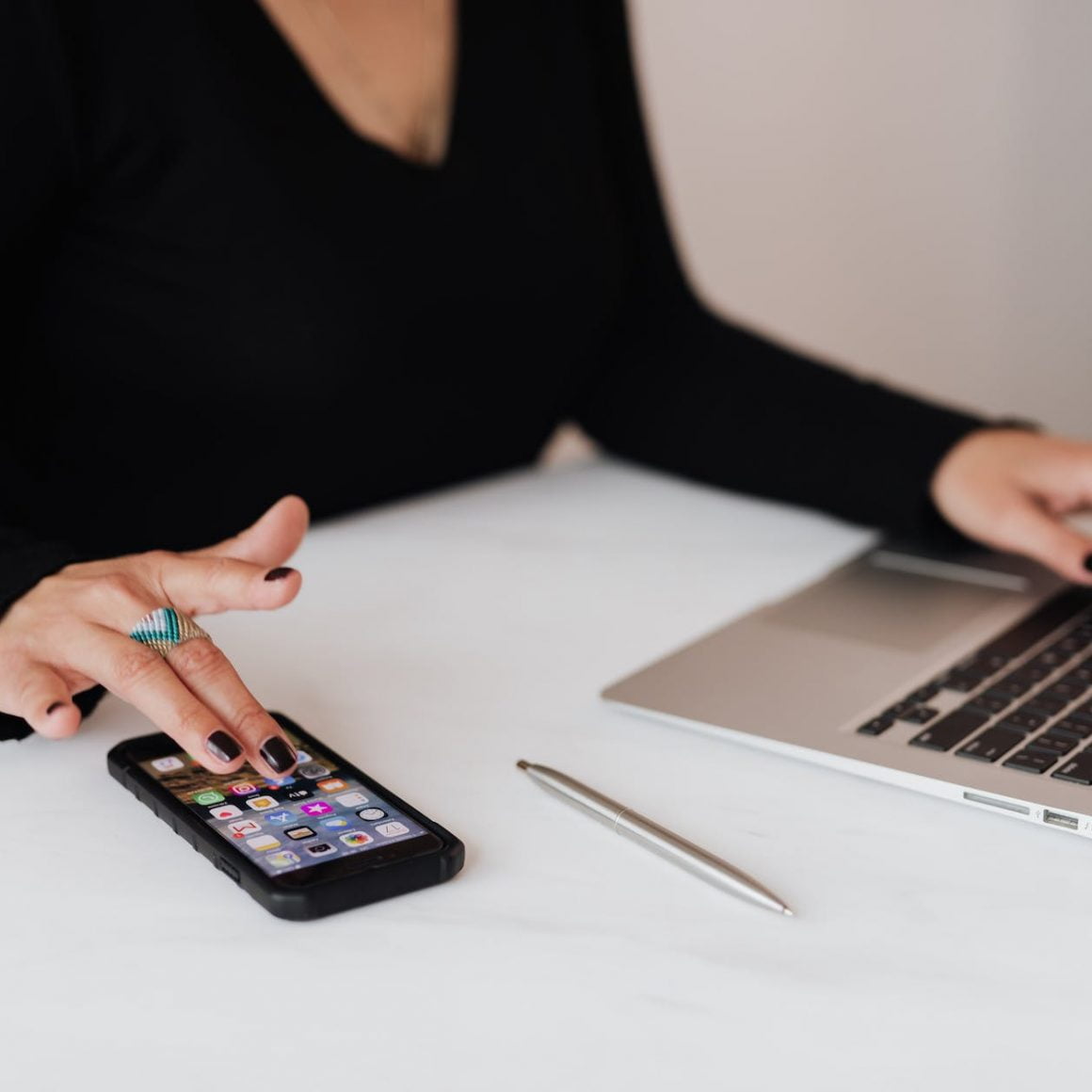 crop woman using smartphone and laptop during work in office