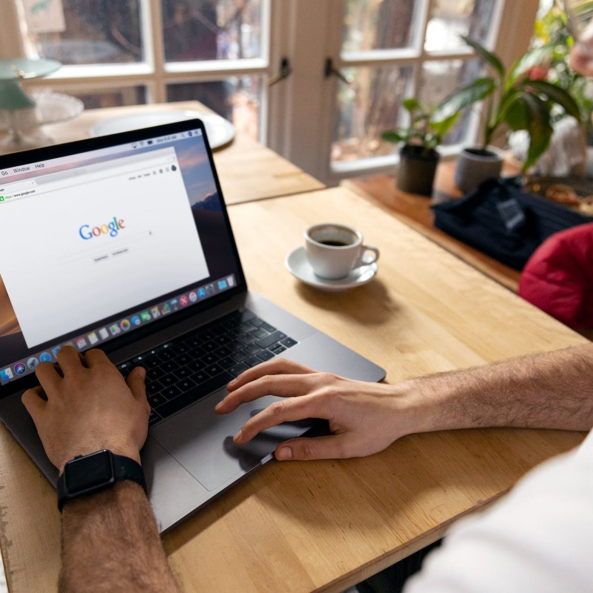 person using macbook pro on brown wooden table