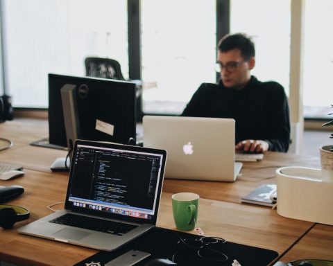 man in black shirt sits behind desk with computers