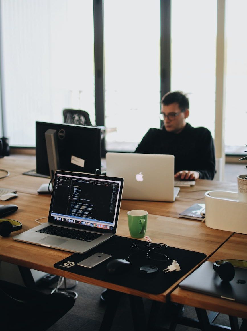 man in black shirt sits behind desk with computers