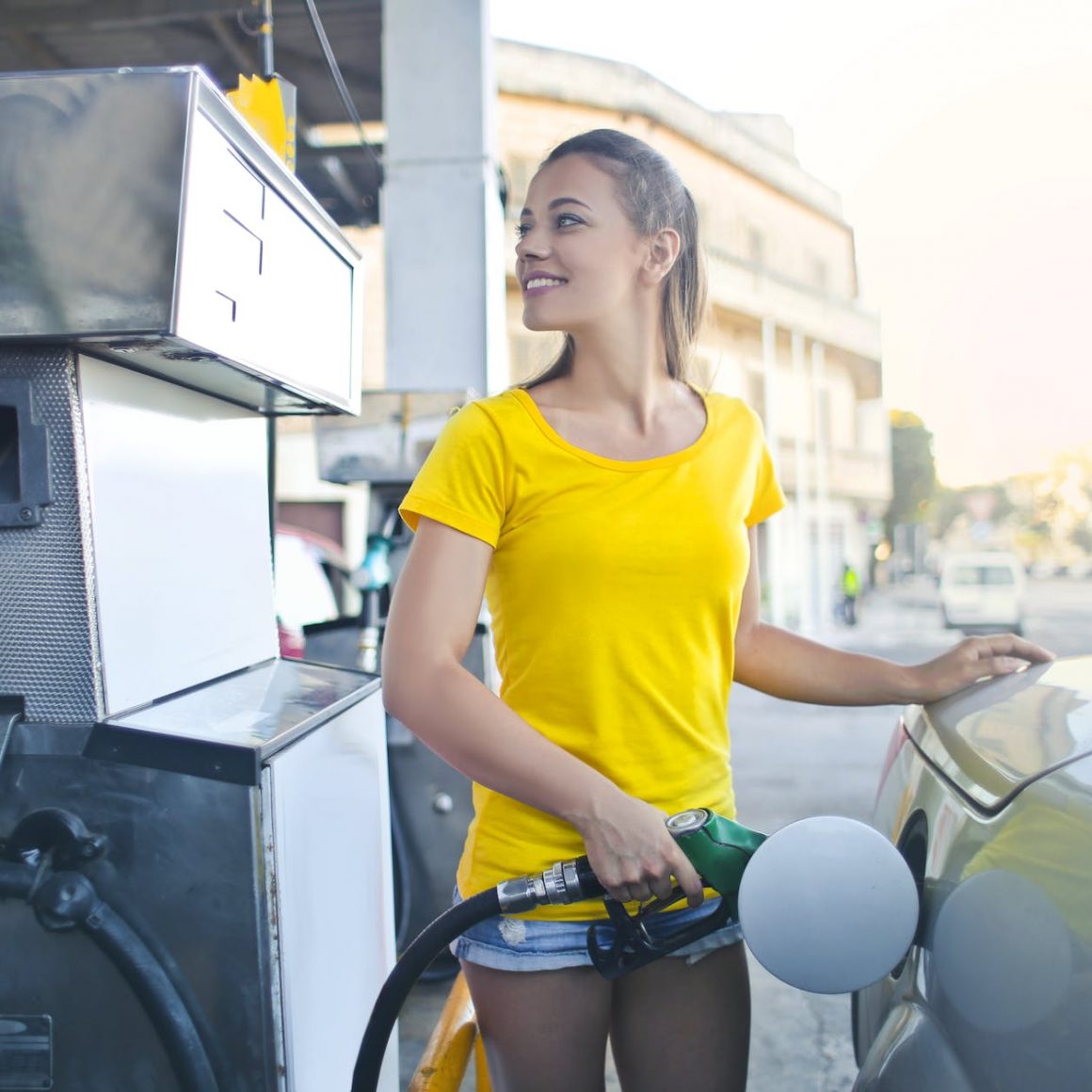 woman in yellow shirt while filling up her car with gasoline