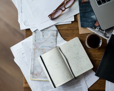 brown framed eyeglasses on white printer paper beside white ceramic mug