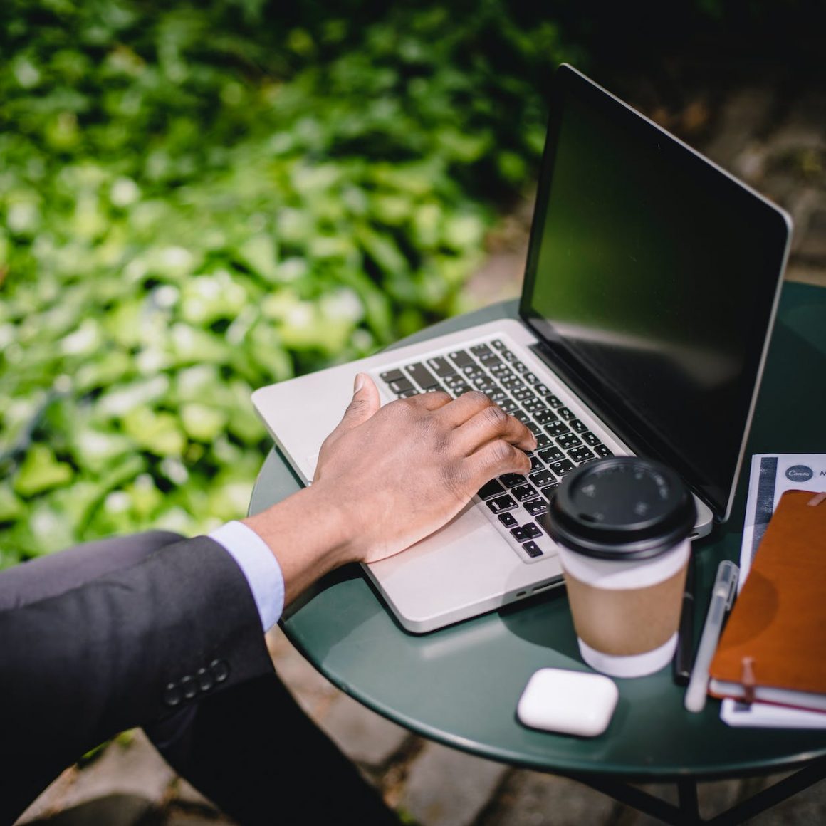 crop male freelancer working on laptop in street cafe on sunny day