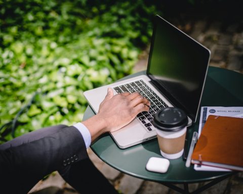 crop male freelancer working on laptop in street cafe on sunny day