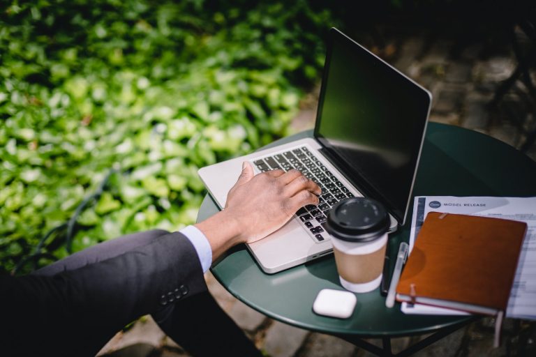 crop male freelancer working on laptop in street cafe on sunny day
