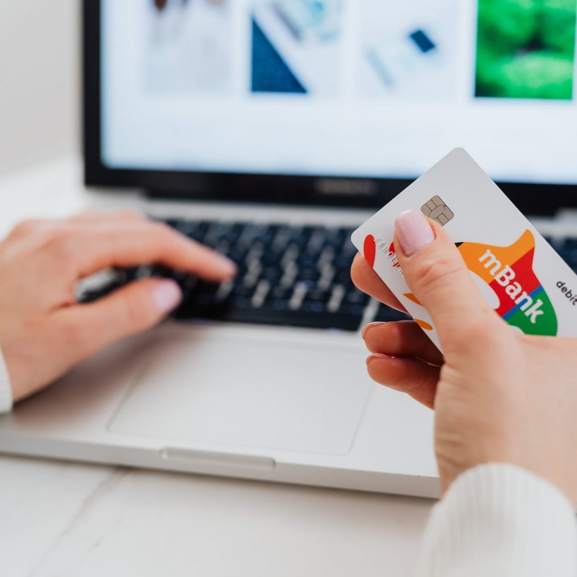 close up shot of a person using a laptop while holding a credit card