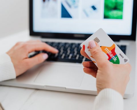 close up shot of a person using a laptop while holding a credit card
