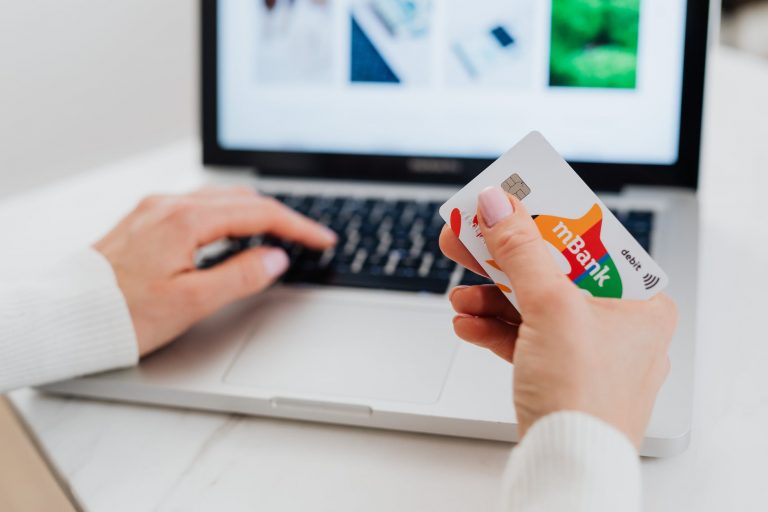close up shot of a person using a laptop while holding a credit card